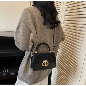 Detail of leopard print flap on black handbag with gold buckle and leather strap