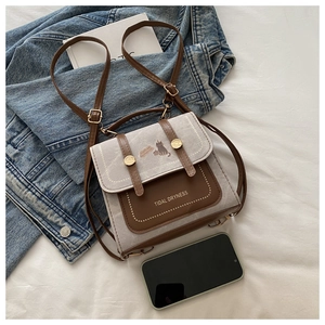 Close-up of canvas and brown leather crossbody bag with cute cat and letter prints