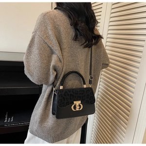 Chic leopard print flap handbag styled with casual grey knitwear in a minimalist setting
