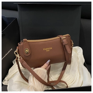 Detail of dark brown pebble leather crossbody bag with golden Fashion Bag print and hardware