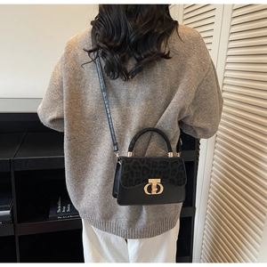 Detail of elegant black leopard print crossbody bag with golden metal clasp hardware