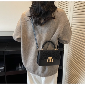 Detail of leopard print flap and golden metal clasp on black crossbody handbag