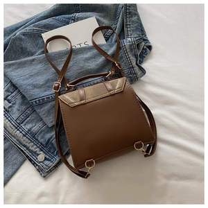 Detail of vintage brown shoulder bag with white dots and gold hardware on white cloth