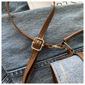 Detailed view of denim fabric texture with golden stitching and brown leather strap buckle