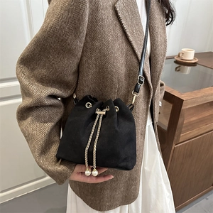 Chic black matte bucket bag with golden chain drawstring and elegant pearl charms