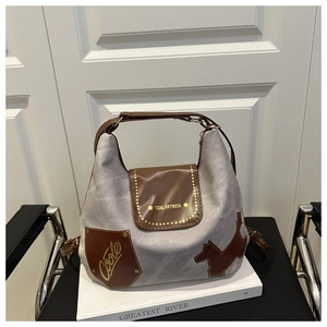 Dettaglio della borsa grigia con patta in pelle marrone e silhouette di cane alla moda