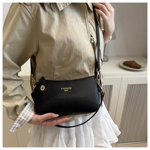 Macro detail of black litchi texture crossbody bag with gold metal clasp and logo