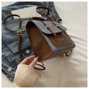Detail of the blue denim and brown leather patchwork bag with buckle closure and print