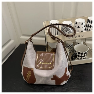 Dettaglio borsa in tela grigia con toppe in pelle marrone e scritta oro Tidal Dryness