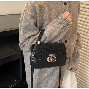 Detail of black leather handbag featuring leopard print flap and gold metal twist lock