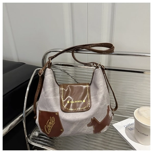 Dettaglio della borsa tote in tela grigia con finiture in pelle marrone e patch a forma di cane