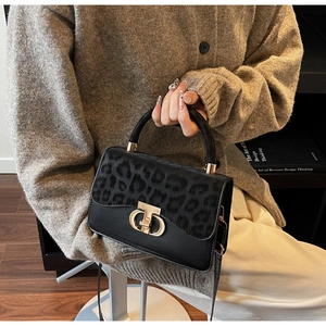 Detail of leopard print handbag featuring a gold arc twist lock and black leather body