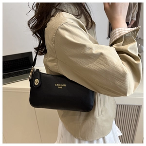 Detail of black pebbled leather handbag with gold metal lock and Fashion Bag lettering