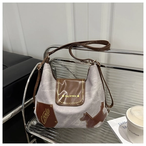 Dettaglio della borsa tote in tela vintage con finiture in pelle marrone e patch grafici