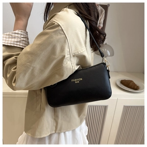 Detail of minimalist black lychee grain leather shoulder bag worn by model in home setting