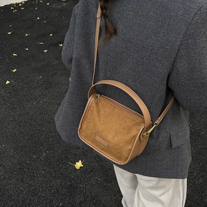 Brown vintage faux suede crossbody bag with leather trim worn by a model in a blazer