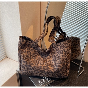 Détail d'un grand sac cabas à imprimé léopard posé sur une table en bois avec miroir