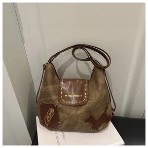 Dettaglio di una borsa tote in tela marrone con patch in pelle a forma di cane e borchie