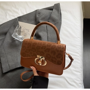 Detail of leopard print flap and gold metal buckle on a brown leather shoulder bag