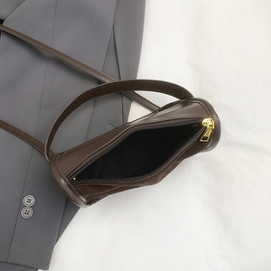 Retro brown leather cylindrical shoulder bag with gold zipper on white background