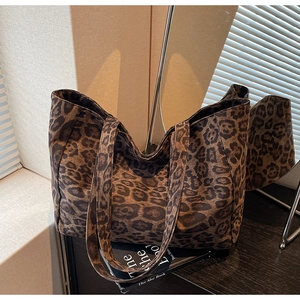 Détail d'un grand sac cabas à imprimé léopard avec de larges anses sur bois
