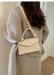 Detail of cream woven crossbody bag with herringbone texture and knotted rope handle