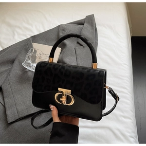 Detail of leopard print flap and golden metal clasp on a black leather handbag