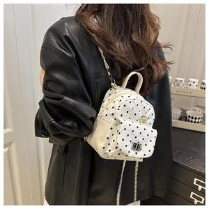 Détail d'un mini sac à dos blanc à pois avec bandoulière chaîne et broderies