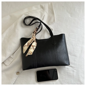 Close-up of black litchi pattern tote bag with printed silk scarf handle detail