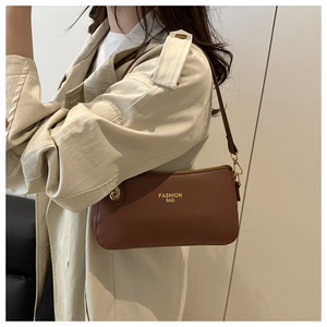 Detail of a brown lychee pattern leather bag with gold hardware and fashion bag text