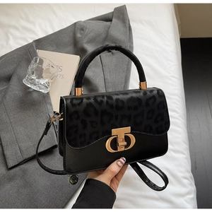 Detailed view of leopard print texture and gold buckle on a black leather handbag