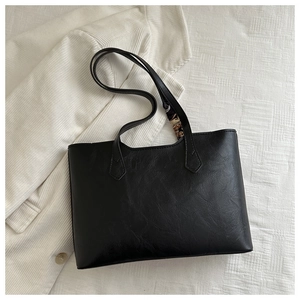 Close-up of black tote bag with lychee grain texture and vintage silk scarf detail
