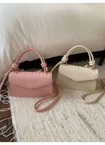 Detailed view of woven texture and knot handle on pink and cream handbags