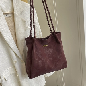 Large burgundy suede tote bag with woven handles shown against a white textured blazer