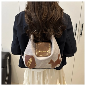 Dettaglio borsa tote argento con finiture in pelle marrone e patch artistica a cane