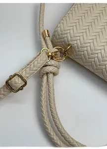 Detail of cream woven leather bag with adjustable strap and gold metal buckle
