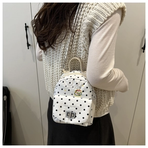 Détail d'un mini sac à dos blanc à pois noirs avec chaîne en métal et fermoir