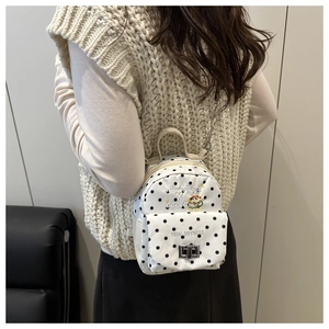Mini sac à dos en toile à pois noirs et chaîne en métal porté au dos par un mannequin