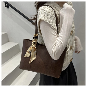 Detail of vintage brown tote bag with marble texture and silk scarf on a model