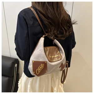 Dettaglio della borsa tote in tessuto grigio opaco e pelle marrone con rivetti e scritte