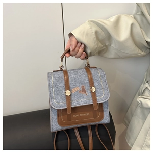 Detail of grey textured crossbody bag with brown leather straps and cat illustration