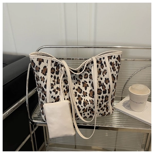 Leopard print tote bag with white faux leather trim and matching zip pouch on metal shelf
