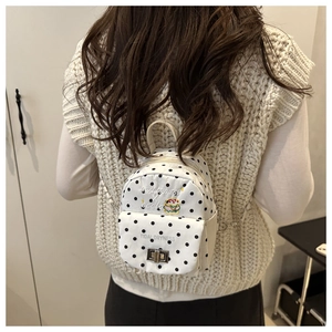 Détails au dos d'un mini sac à dos à pois noir et blanc avec bretelles en chaîne fine