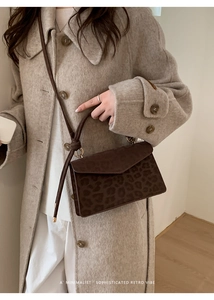 Detail of leopard print handbag with knot strap showing suede texture and envelope flap