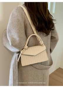 Close-up of beige woven texture handbag with knot detail on grey coat model