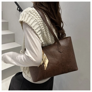 Detail of dark brown leather tote bag with vintage texture and stylish floral silk scarf