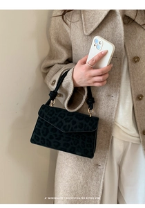 Detail of leopard print handbag with golden metal rings and black top handle
