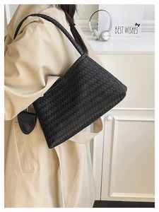 Detailed view of black woven leather texture and crossbody strap on a large shoulder bag