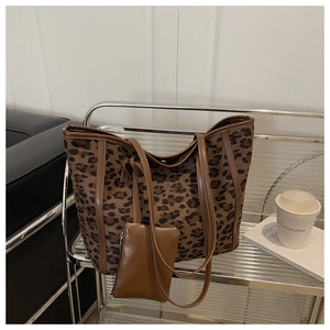 Detail of leopard print tote bag with brown leather handles and a matching mini pouch