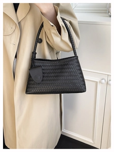 Close-up of black woven leather shoulder bag with texture detail on model arm